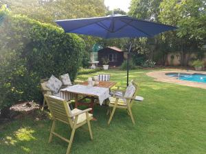 een tafel en stoelen onder een paraplu in een tuin bij Roosboompies Guest Suite in Centurion