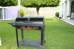 a grill sitting on the grass in a yard at CASA MORADA 24 Personas alberca climatizada Burgos Cuernavaca in Cuernavaca