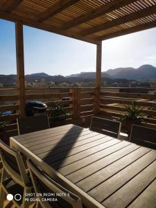 a wooden table and chairs on a deck with mountains at אלת המדברGoddess of the desert in Beʼer Ora