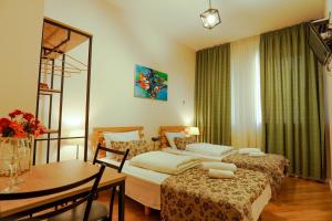 Habitación de hotel con 2 camas y mesa en Check-In Hotel, en Tiflis