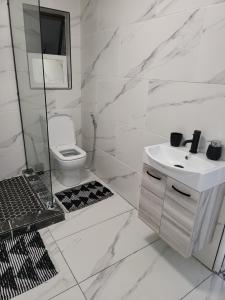a white bathroom with a sink and a toilet at The Greek Beach and Golf House in Southbroom