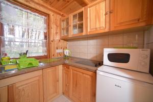 a kitchen with wooden cabinets and a white microwave at Domki Pod Wydmami 40m od plaży in Dźwirzyno