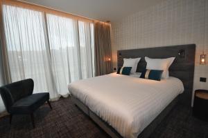 a hotel room with a bed and a chair and window at Hôtel La Maison Bord'eaux in Bordeaux