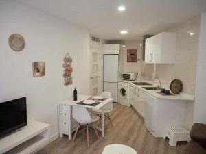 a white kitchen with a table and a counter top at San José Apartamentos Turísticos Miky in Albacete