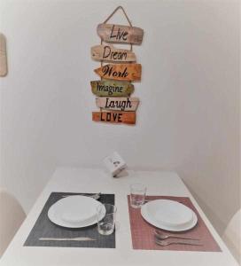 a table with two white plates and a sign at San José Apartamentos Turísticos Miky in Albacete +5 photos