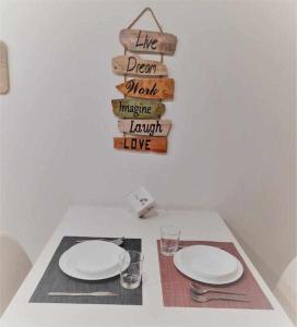 a table with two white plates and a sign at San José Apartamentos Turísticos Miky in Albacete