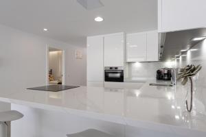 a white kitchen with a large white counter top at BLUE SEA II - FRONT BEACH in Puerto de Mogán