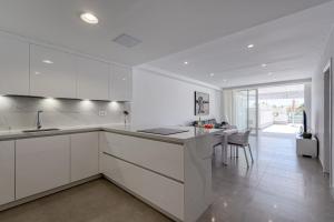 a white kitchen with a counter and a dining room at BLUE SEA II - FRONT BEACH in Puerto de Mogán