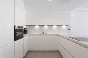 a white kitchen with white cabinets and a sink at BLUE SEA II - FRONT BEACH in Puerto de Mogán +22 photos