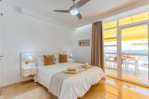 a white bedroom with a bed and a balcony at BLUE SEA I in Puerto de Mogán