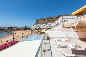 Un balcón con sillas y una piscina y una playa. en BLUE SEA I, en Puerto de Mogán