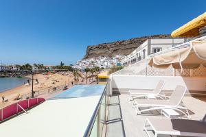 a balcony with chairs and a swimming pool and a beach at BLUE SEA I in Puerto de Mogán