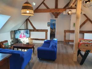 un soggiorno con divano blu e TV di Le Gîte des Globe-Trotters pour 15 pers a Commenailles