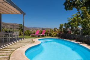 a swimming pool with pink chairs and a table and chairs at VILLA SALOBRE in Salobre
