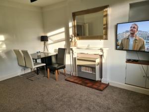 sala de estar con TV, mesa y chimenea en Lovely self-catering apartment in city centre, en Dumfries