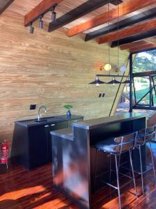 a kitchen with a sink and a bar with stools at Estalagem La Hacienda in Gramado