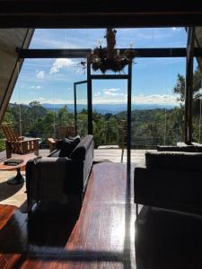 uma sala de estar com sofás e uma grande janela de vidro em Estalagem La Hacienda em Gramado