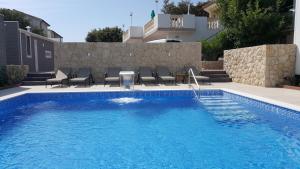 a swimming pool with chairs next to a house at Premium Appartments Suha Punta in Rab