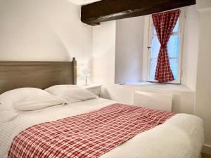 a bed with a red and white blanket and a window at Le Cocon Petite France in Strasbourg
