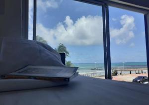 un libro en una cama con vistas a la playa en Puleiro Hostel en Salvador