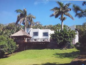 a white house with palm trees on a lawn at The Greek Beach and Golf House in Southbroom