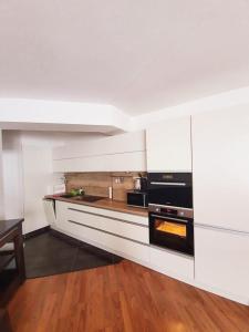 una cucina con pareti bianche e pavimenti in legno di Apartmán 27, Kamzík a Donovaly