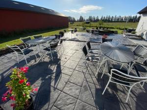 un patio con sillas, mesas y una sombrilla en Billund-BnB ApS, en Billund