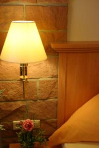 a lamp with a vase of flowers next to a bed at Birnbaumhof - Hotel Pension und Ferienwohnungen in Schwedelbach