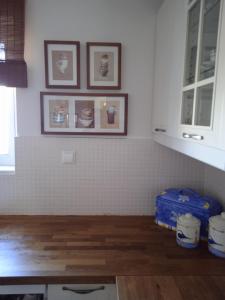 a kitchen with white tiled walls and wooden floors at Calma in Perdika