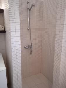 a shower in a bathroom with white tile at Calma in Perdika