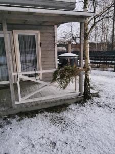 a porch of a house with a tree in the snow at Holiday Home Kolka in Kolka