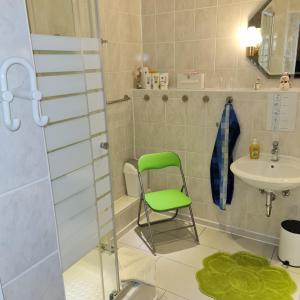 a bathroom with a green chair and a sink at Ferienwohnung Wendehake in Quedlinburg