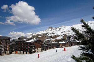 two people skiing in the snow in front of a mountain at La Grande Ourse - 4 pièces, 6 personnes in Méribel