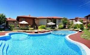 a swimming pool with chairs and umbrellas in front of a house at Garden of Eden Complex in Sveti Vlas