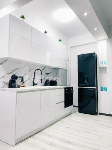 uma cozinha com armários brancos e um frigorífico preto em Diamond apartment em Tessalônica