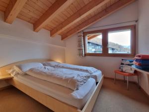 1 dormitorio con 2 camas y ventana en Snowfun B Penthouse, en Saas-Fee