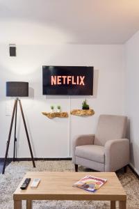 a living room with a chair and a netflix sign on the wall at West Garden At Aigio By Greece Apartments in Aigio