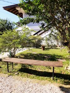 un banco de madera sentado en la hierba bajo un árbol en Residencial de Los Pájaros, en Florianópolis