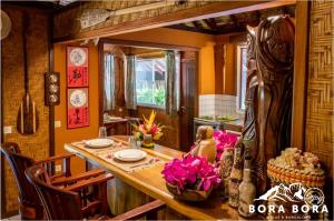une salle à manger avec une table en bois et des fleurs roses dans l'établissement Villa Bora Bora - on Matira, à Bora Bora