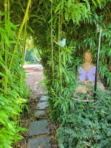 een tuin met een standbeeld in een plantentunnel bij Purple Papillon in Heuvelland