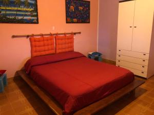 1 dormitorio con 1 cama roja y armario en Andrebyke terrace en Gergei