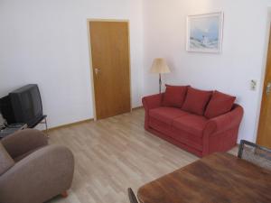 ein Wohnzimmer mit einem roten Sofa und einem TV in der Unterkunft Hexenstieg House Lerbach in Osterode