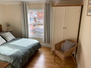 ein Schlafzimmer mit einem Bett, einem Stuhl und einem Fenster in der Unterkunft Lovely apartment in beautiful coastal village in Weybourne