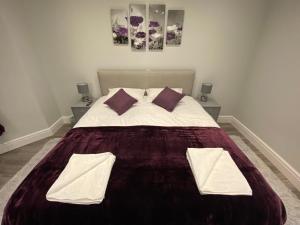 1 dormitorio con 1 cama grande con sábanas blancas y almohadas moradas en Edward Place Luxury Hot Tub Apartments en Blackpool