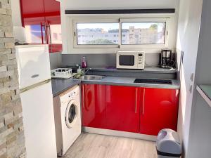 una piccola cucina con armadi rossi e forno a microonde di AiguesMarines a Cagnes-sur-Mer