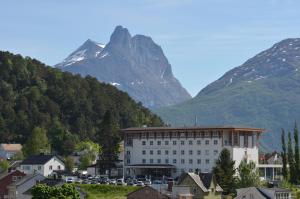ein großes weißes Gebäude mit einem Berg im Hintergrund in der Unterkunft Grand Hotel - by Classic Norway Hotels in Åndalsnes