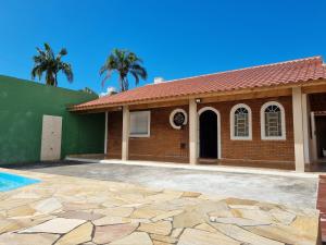 Casa de ladrillo con techo de baldosa y piscina en Confortável casa com piscina e churrasqueira a 100m da praia, en Caraguatatuba