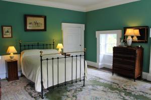 a bedroom with green walls and a bed and a dresser at Roundwood House in Mountrath