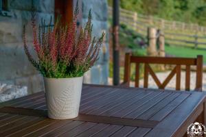 a white vase with flowers sitting on a wooden table at Agroturystyka Corno Owca in Żabnica