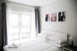 - une chambre blanche dotée d'une fenêtre et d'un lit avec des oreillers blancs dans l'établissement Windmill Lane 002, à Dublin
